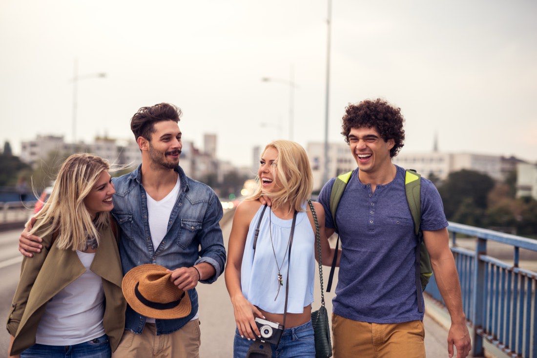 Four friends walking across a city bridge